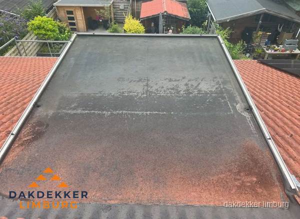 Verouderd plat dak met slijtage tussen schuine daken in Limburg Verouderd plat dak met slijtage tussen schuine daken in Limburg